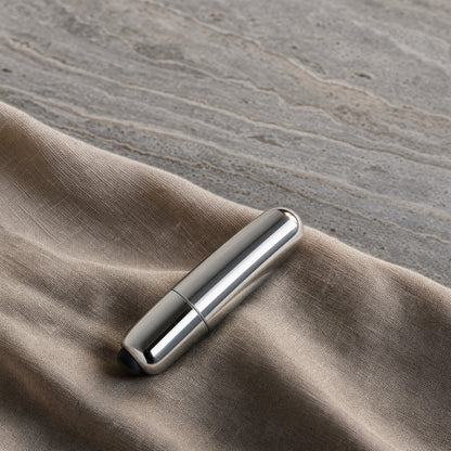 Mini balle vibrante argent sur du lin, fond travertin gris
