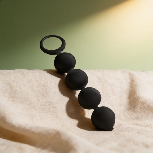 CHAPELET ANAL LENNON 4 SPHÈRES SILICONE 15 CM — posé sur du lin drapé, lumière chaude éditoriale