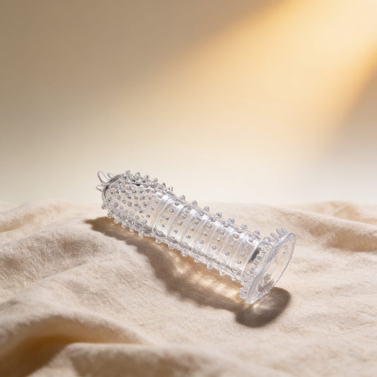 GAINE PÉNIENNE AVEC POINTS STIMULANTS TRANSPARENTS 14 CM — photo éditoriale sur lin drapé