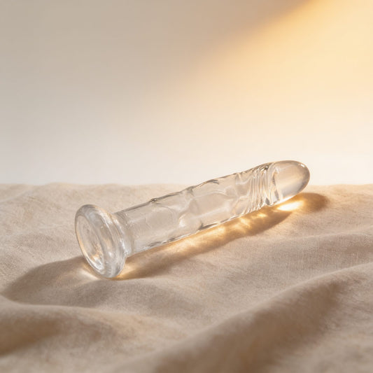 Gode ventouse transparent 18 cm — posé sur du lin drapé, lumière chaude