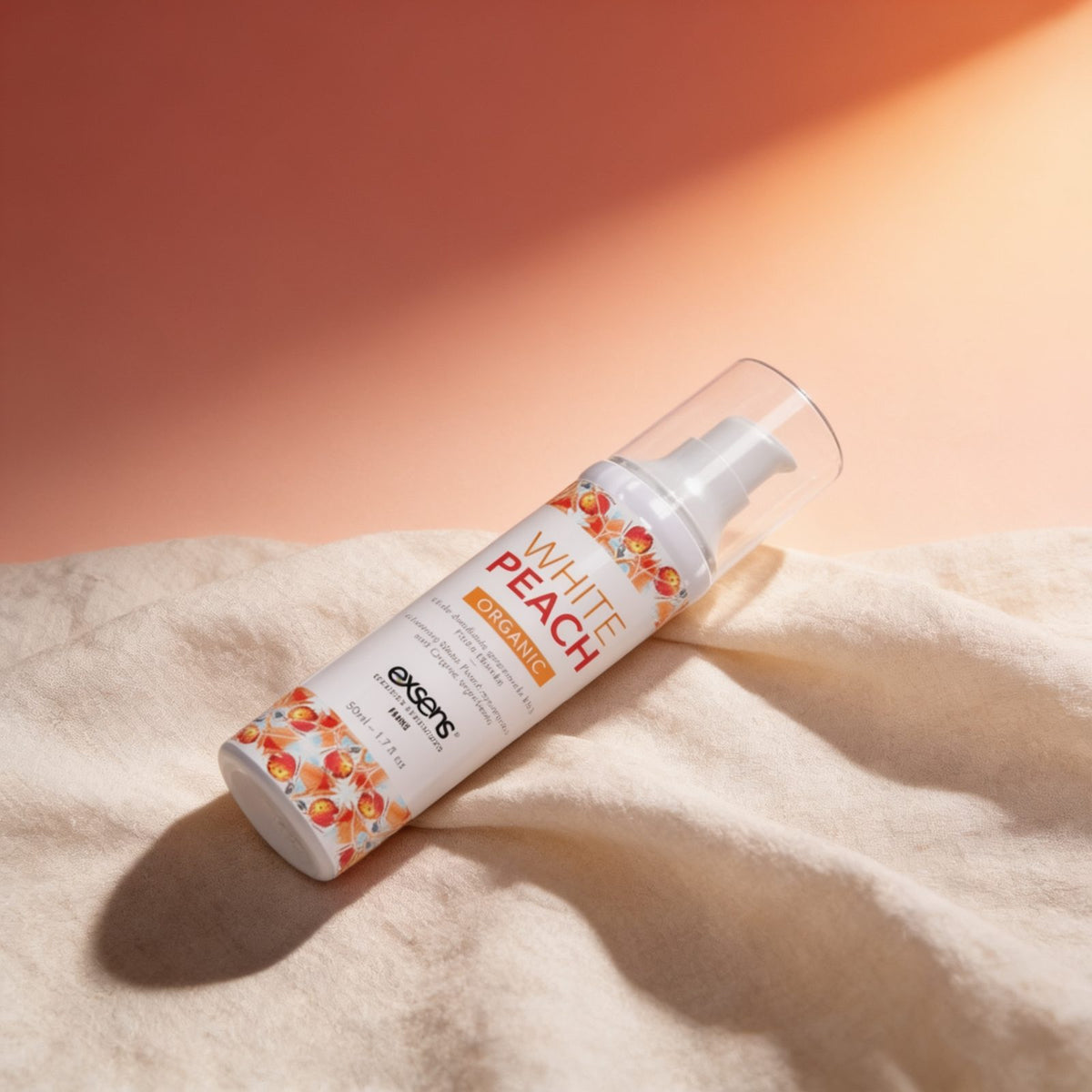 Huile de massage pêche blanche bio — posée sur du lin drapé, lumière chaude