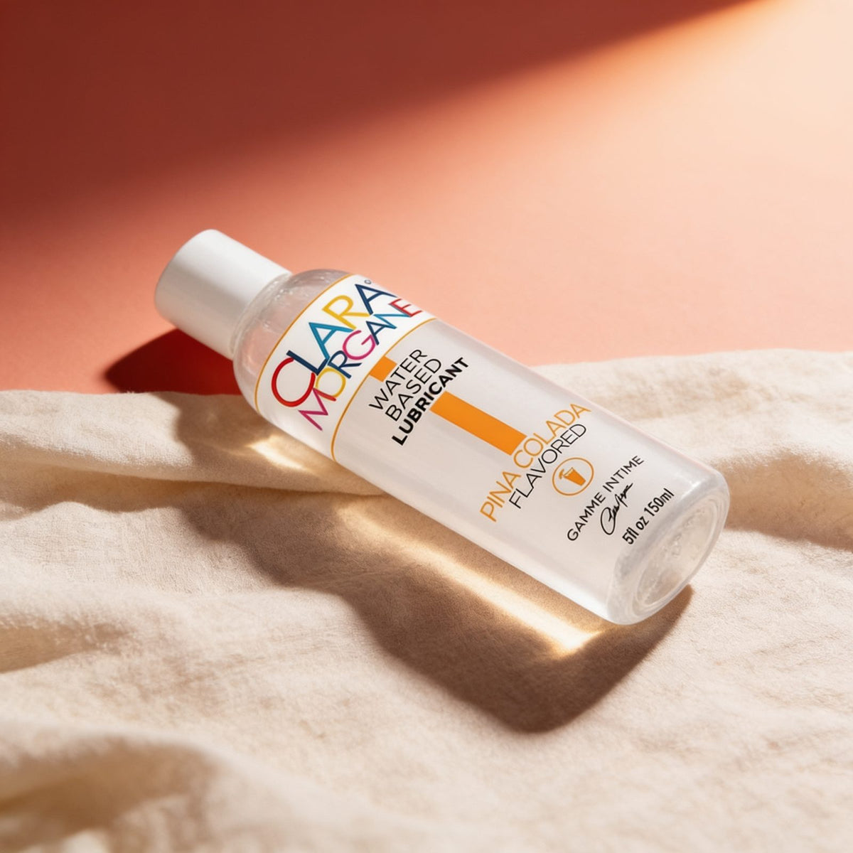 Lubrifiant PINA COLADA 150ml Clara Morgane — photo éditoriale sur lin drapé
