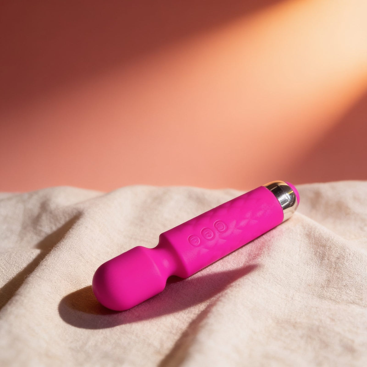 Vibromasseur wand rose 20 vitesses USB Yoba — posé sur du lin drapé, lumière chaude
